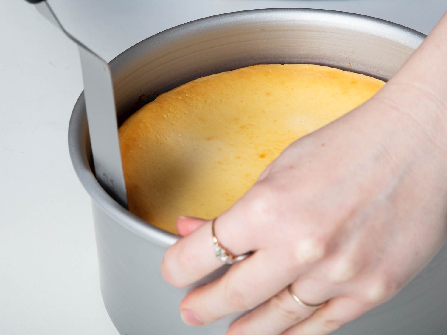 把烤好的芝士蛋糕从锅里拿出来，用一个大的抹刀，沿着锅的内部边缘刮
