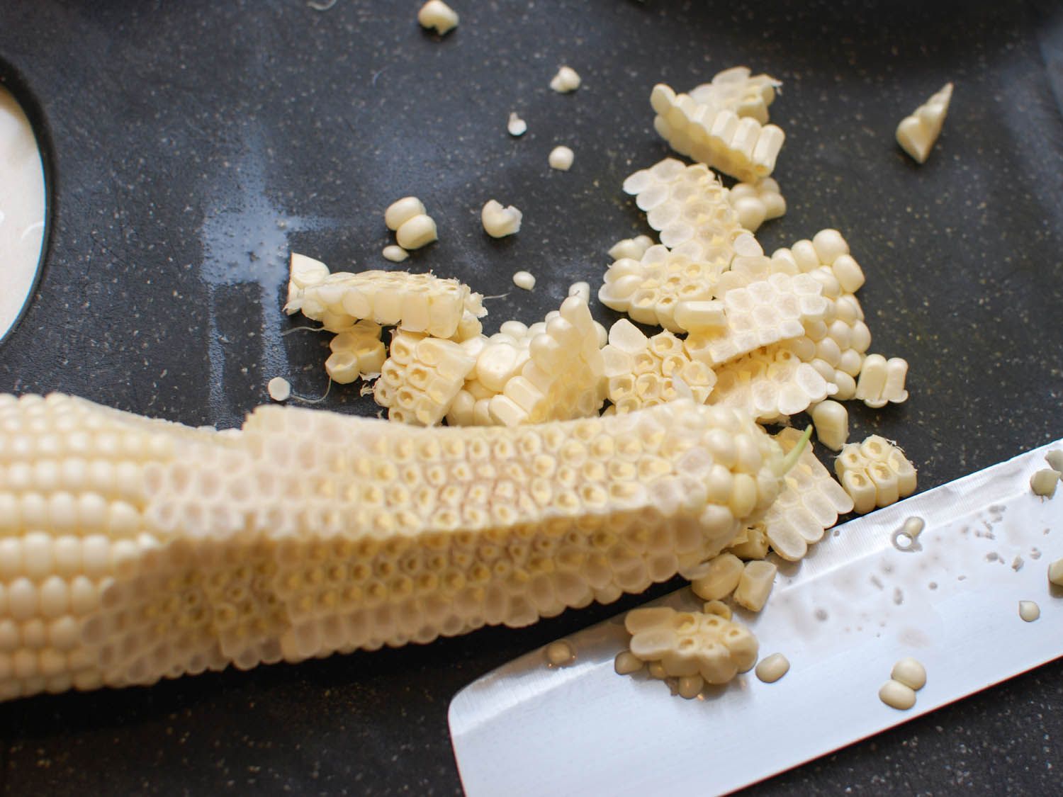 用厨师刀从玉米棒子上切下甜玉米。