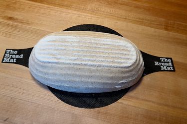 a loaf on a bread mat on a wood surface