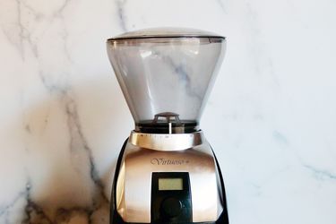 the top half of a coffee grinder framed against a white marble background