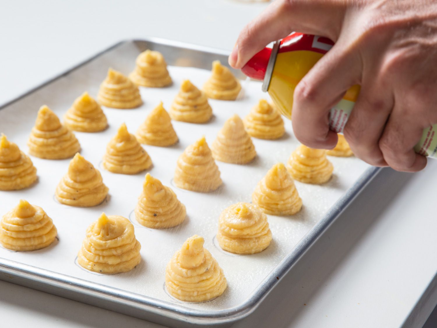 Nonstick cooking spray is applied to the choux paste mounds