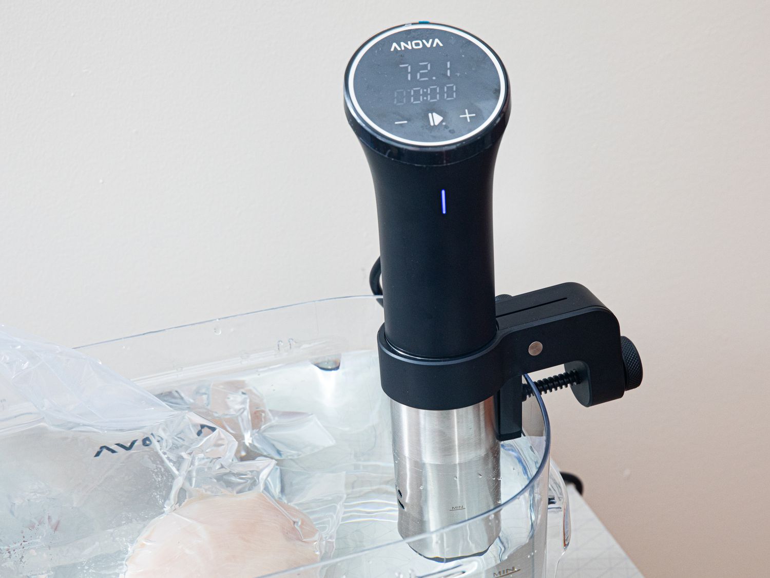 the anova precision cooker sous vide on a cambro with a plastic wrapped chicken cooking in the water bath