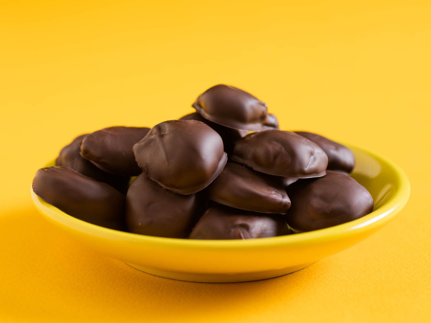 A yellow dish of homemade milk duds set on a yellow background.