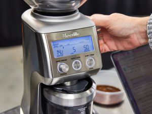 A person adjusting the grind setting of a breville coffee grinder