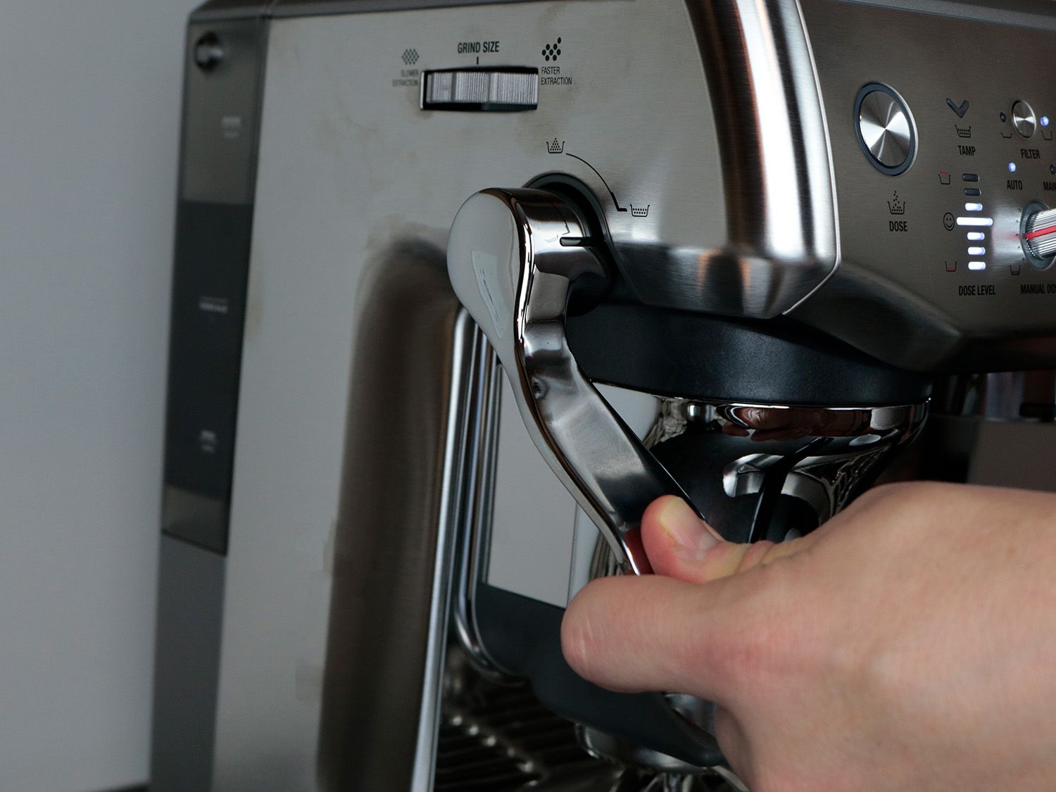 a lever on an espresso machine is pressed down, tamping a coffee puck