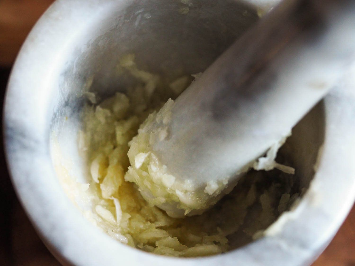 Crushed garlic in a mortar, with the pestle inside as well.