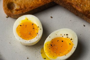 一个完美的半熟鸡蛋，切成两半露出溏心的蛋黄，图片上方是烤面包。gydF4y2Ba