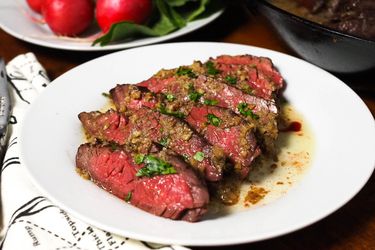 Rare, sliced steak with bagna cauda on a white plate.