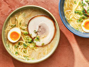 A bowl of homemade tonkatsu ramen topped with a marinated egg which has been sliced in half, and a slice of pork chashu.