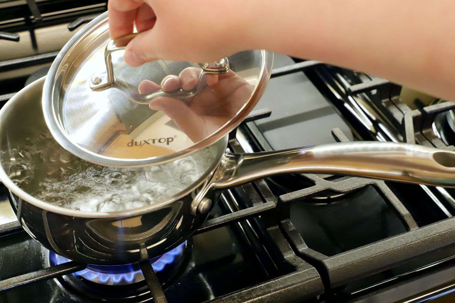 一个人打开正在烧水的小炖锅的盖子