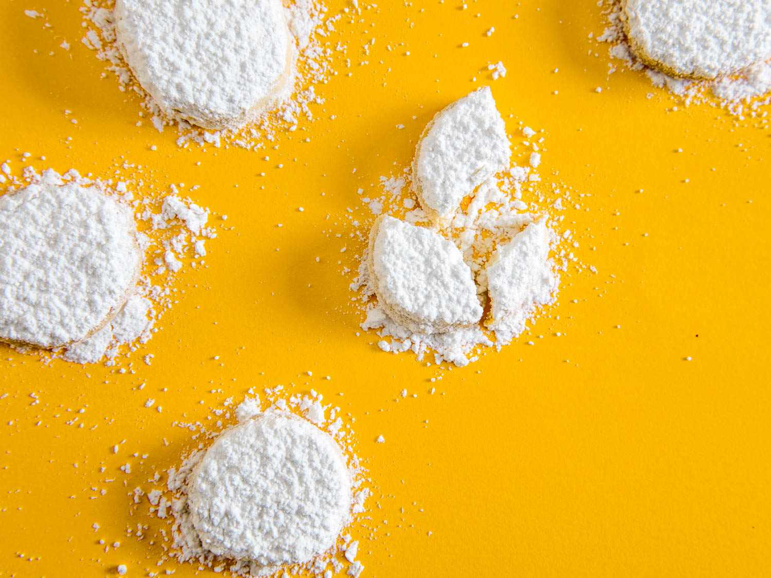 Powdered sugar-covered lemon meltaway cookies against a yellow background