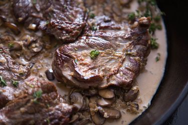 Seared skirt steak in a skillet full of creamy pan sauce and mushrooms
