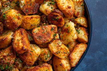 The best crispy roast potatoes ever in a bowl on a blue background.