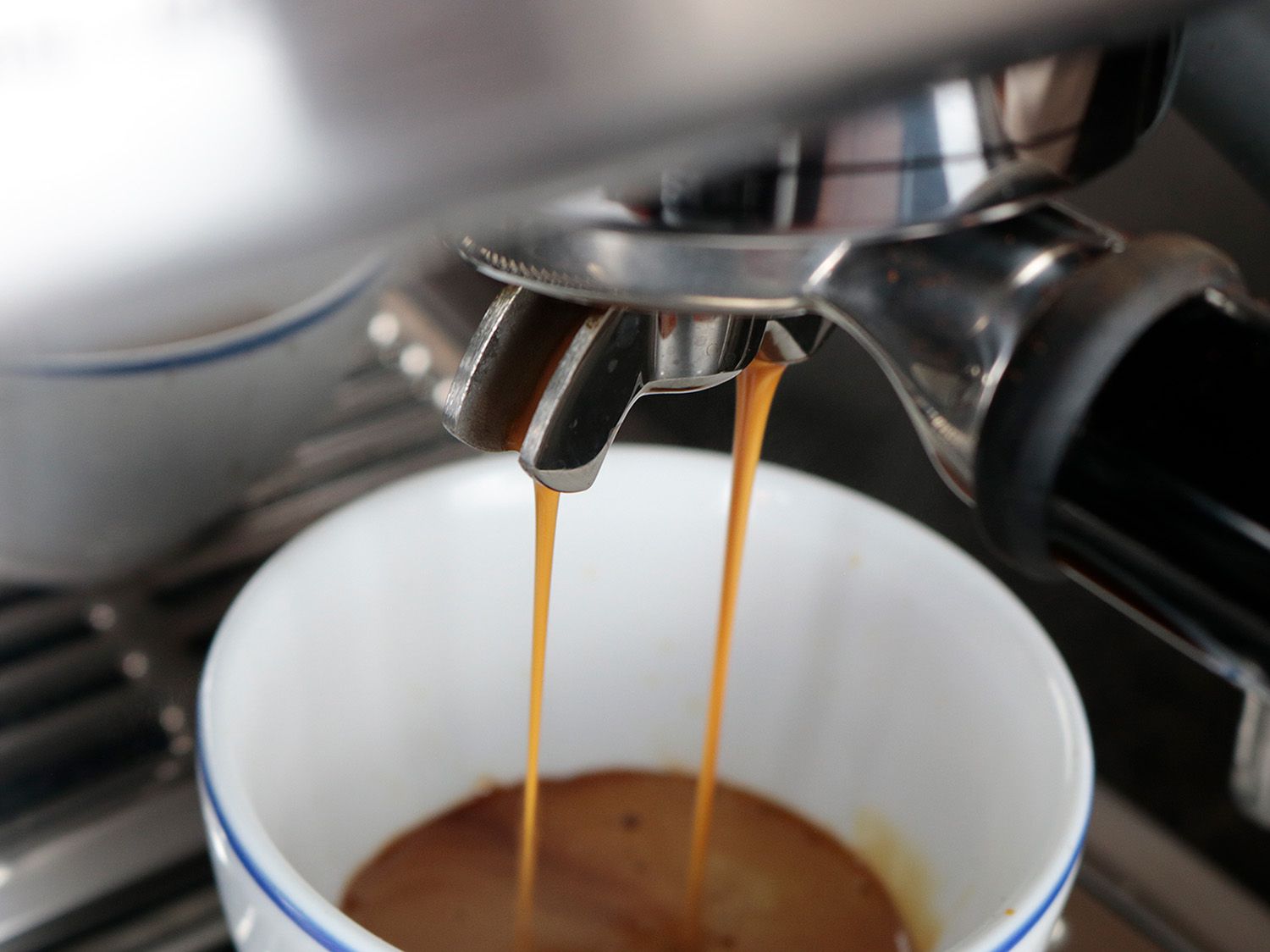 an espresso machine portafilter showing two streams of espresso falling off of the spouts