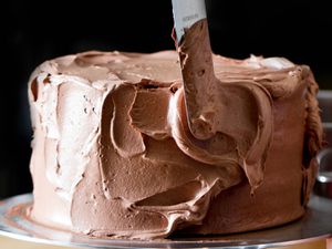 Frosting a cake with chocolate Swiss buttercream.