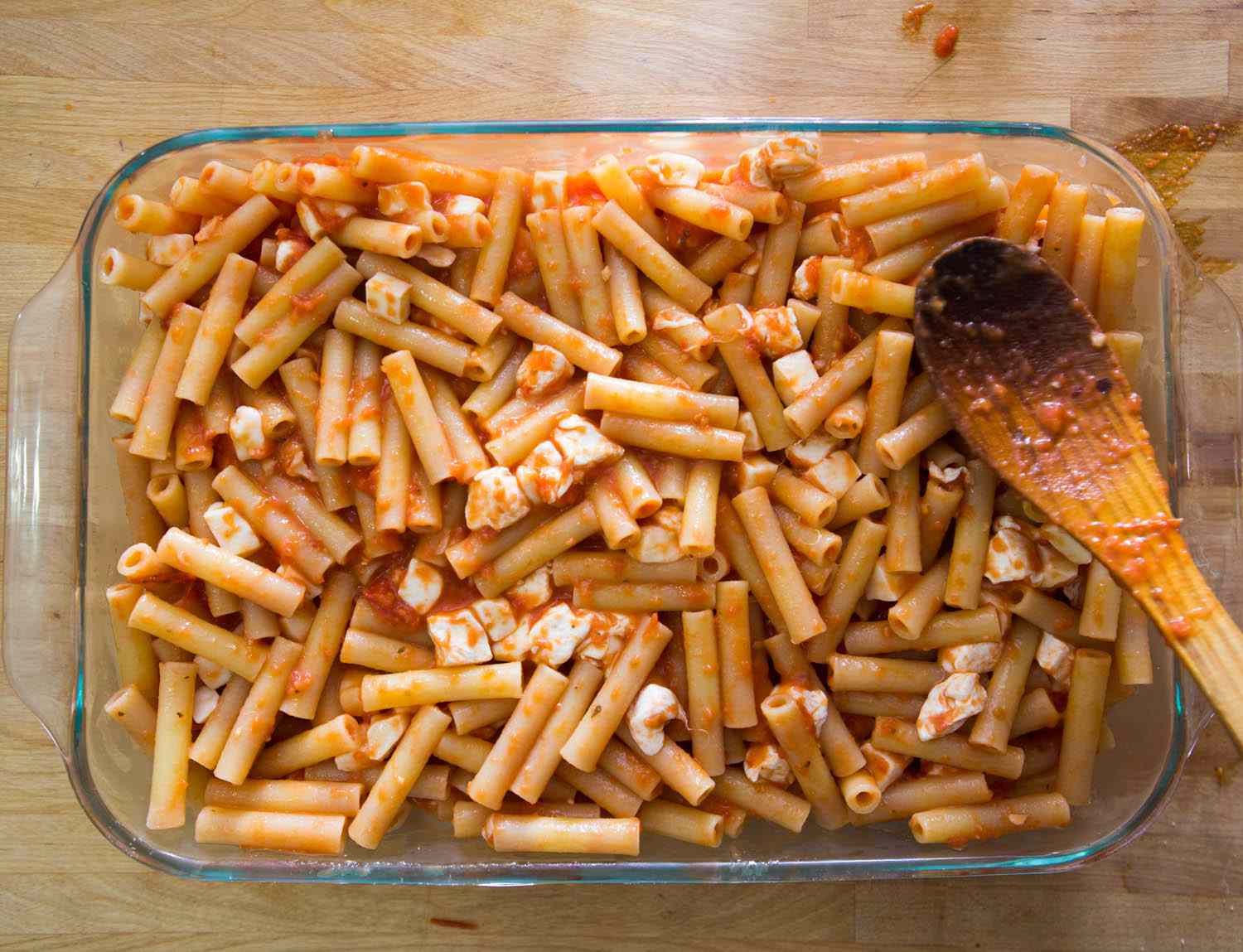 意大利面涂上酱汁，放在烤盘中，撒上马苏里拉奶酪块。