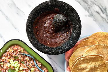 Overhead view of salsa negra in a molcajete with tostadas and ceviche