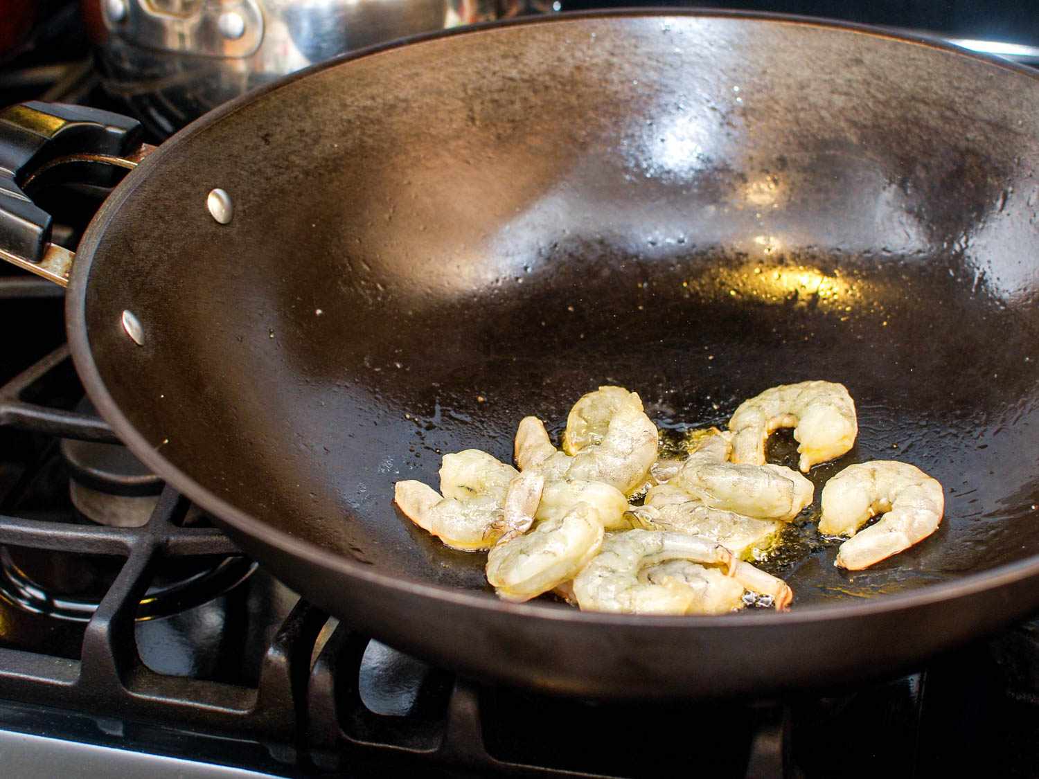 Partially cooked shrimp in a hot wok.