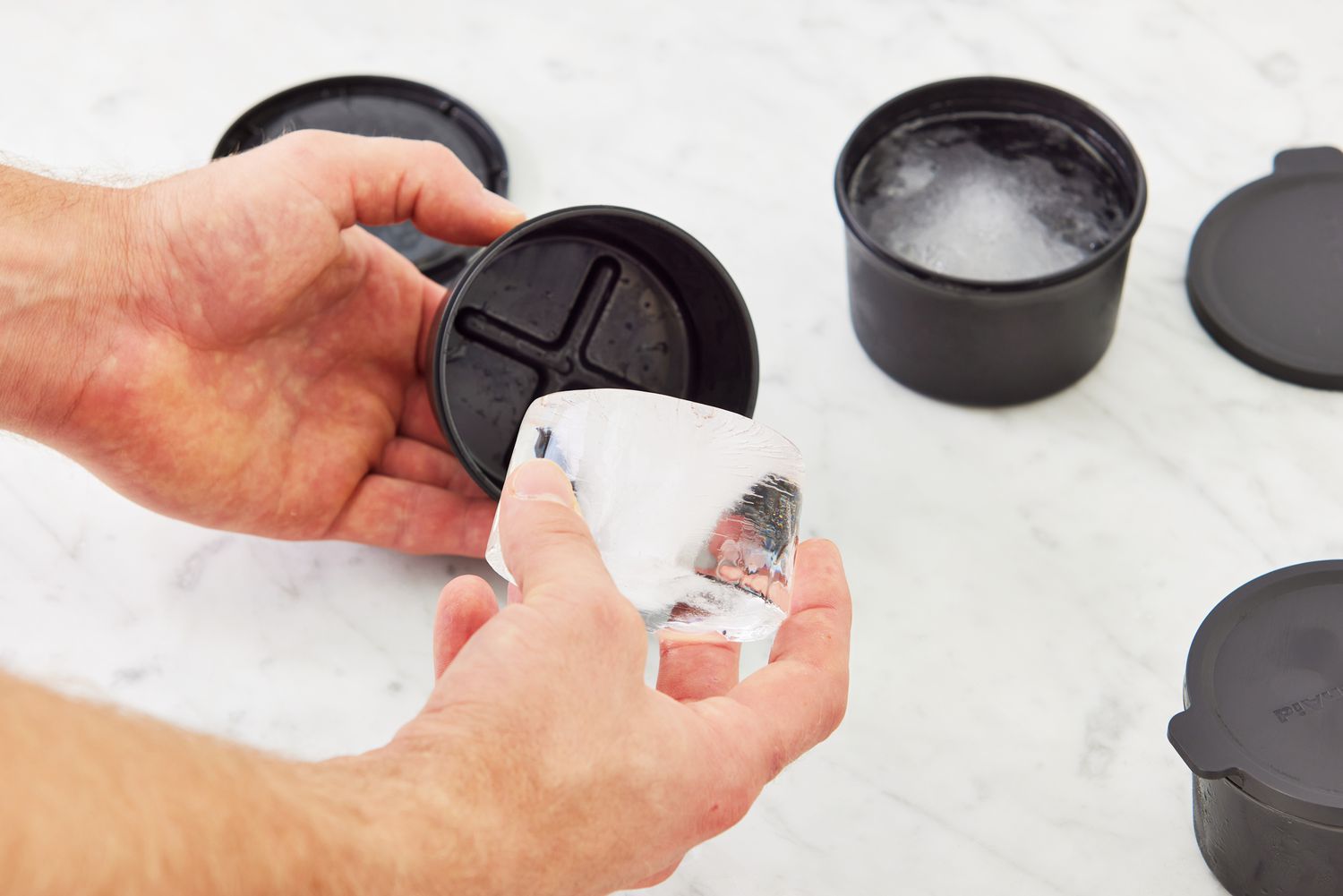 a person removing a puck of ice from its mold