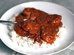 A plate of shrimp tikka masala over rice.