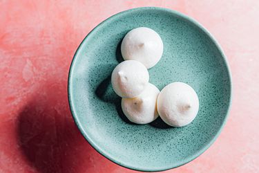 aquafaba-cardamom meringue cookies on a blue plate on a pink background