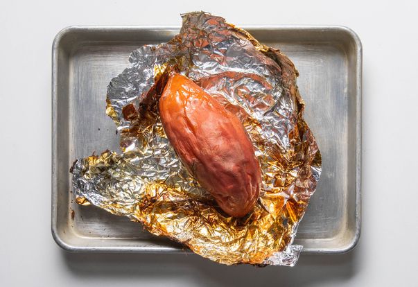 Frozen roasted sweet potato on foil in a rimmed baking sheet