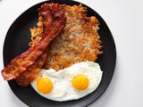 Crispy shredded hash browns with sunny-side up eggs and bacon