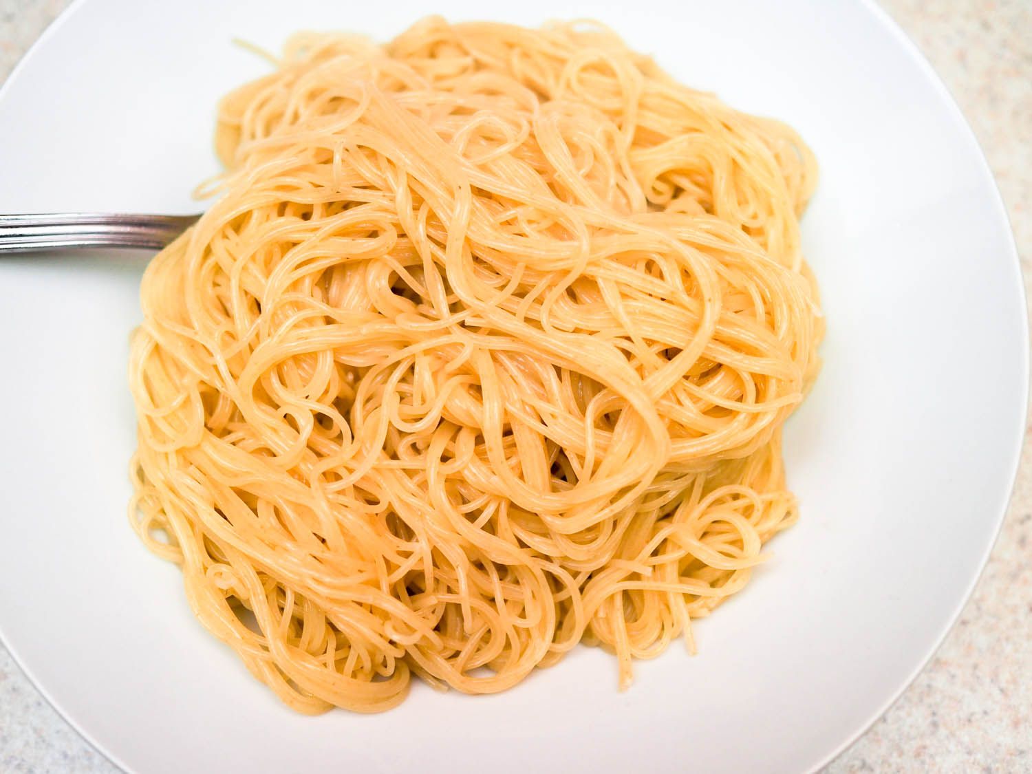 A plate with a pile of angel hair pasta cooked with baking soda.