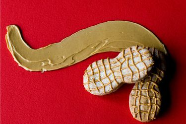 Two homemade Nutter Butter cookies arranged against a wavy streak of peanut butter