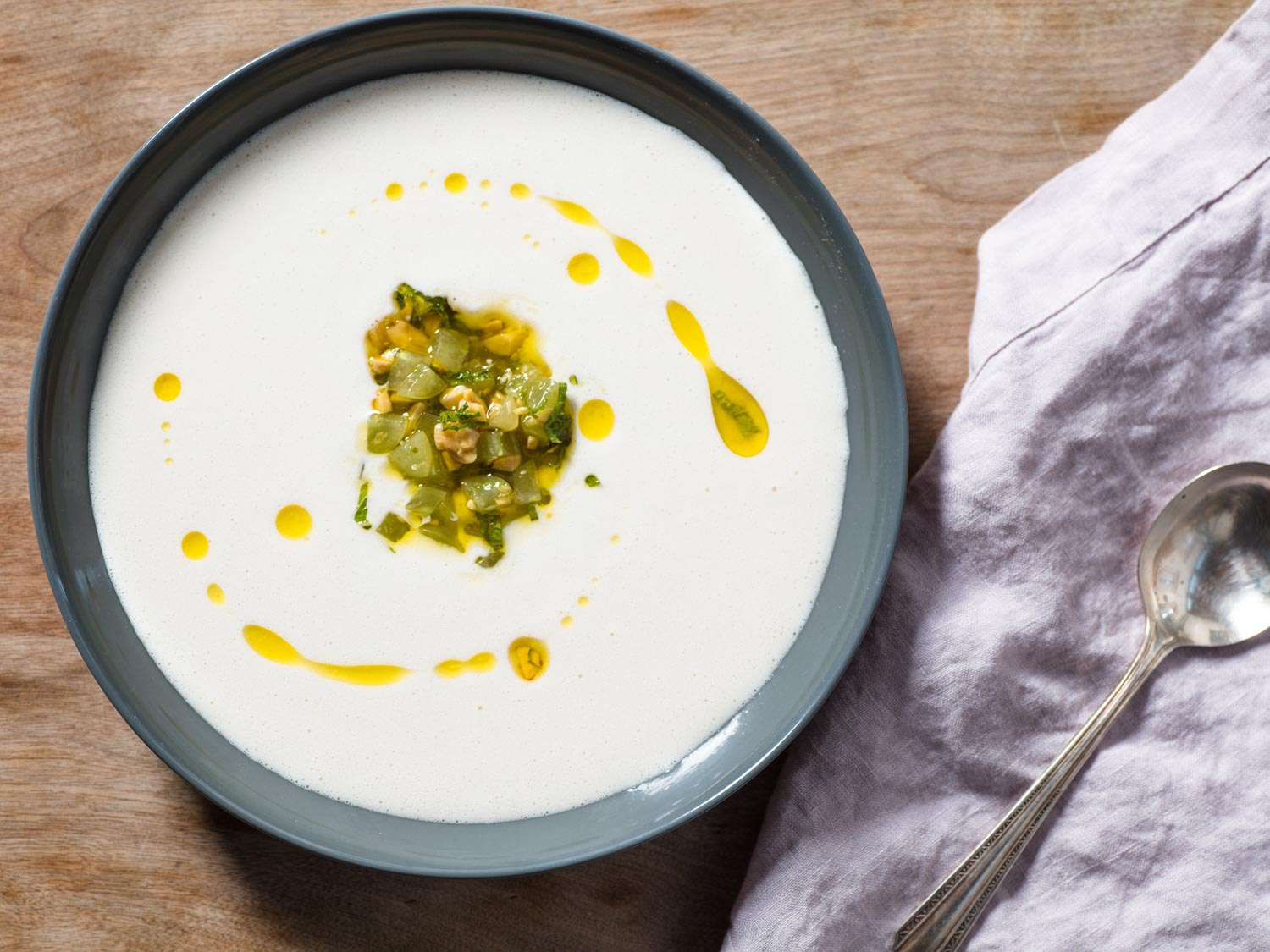 A bowl of ajo blanco, garnished with green grapes and a drizzle of olive oil.