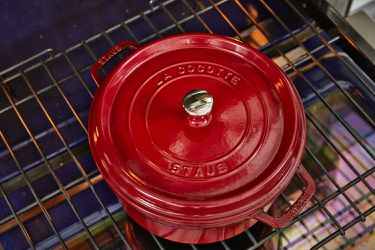 a red Staub dutch oven on an oven's rack