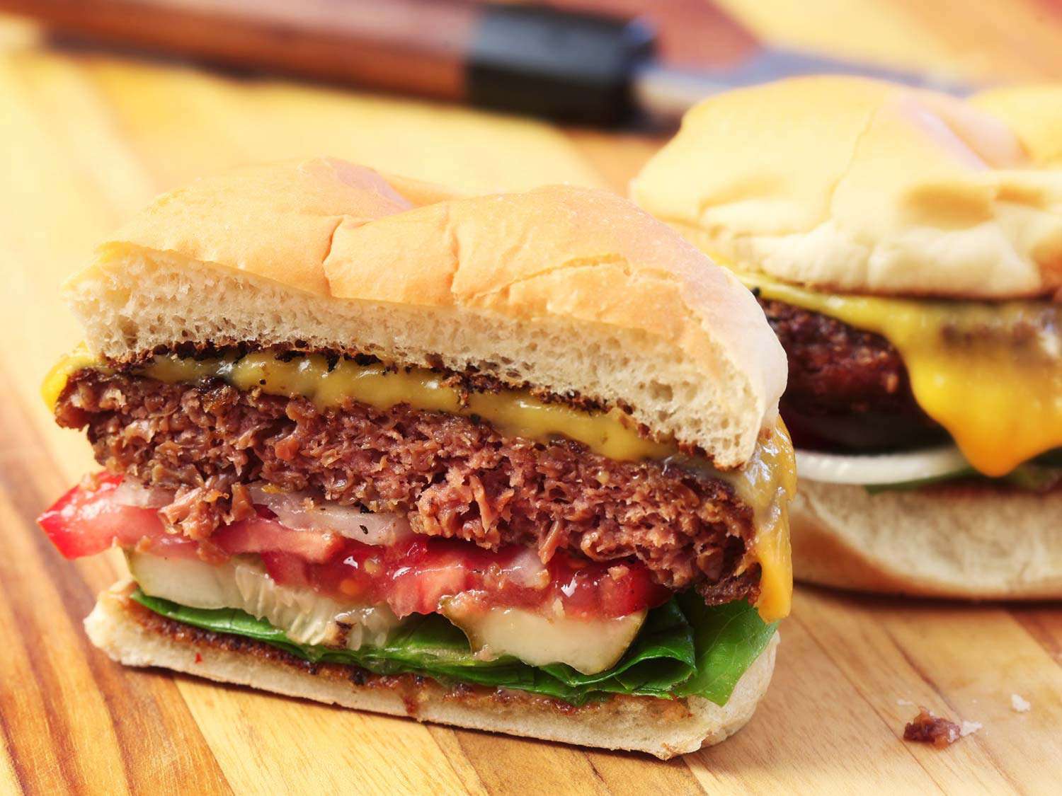 用Beyond Meat切成两半放在砧板上的芝士汉堡。