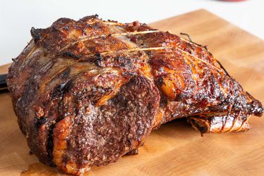 A whole cooked prime rib roast resting on a cutting board.