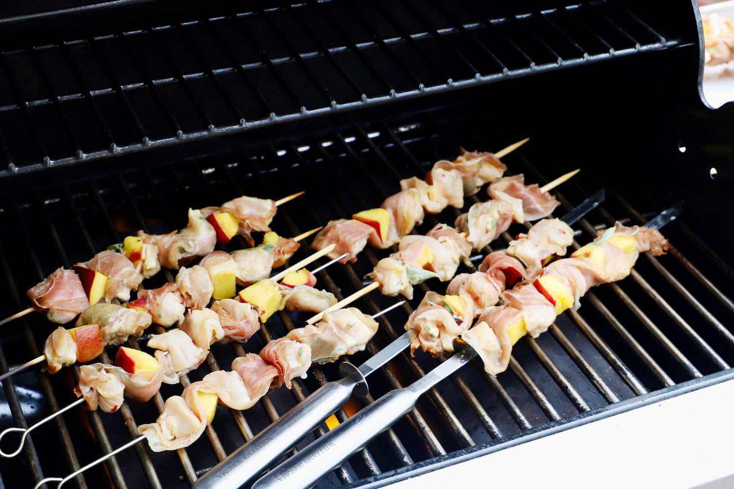 bamboo and stainless steel skewers cooking on a small gas grill