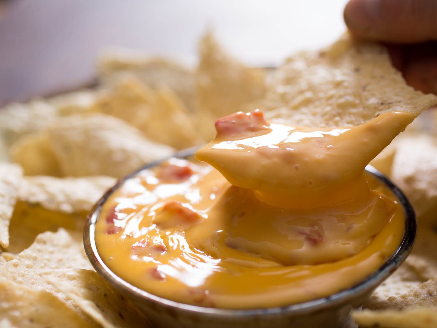 A tortilla chip dipping into Texas-style queso dip, made with process cheese.