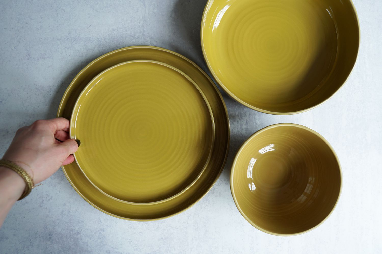 A hand placing a plate onto another plate