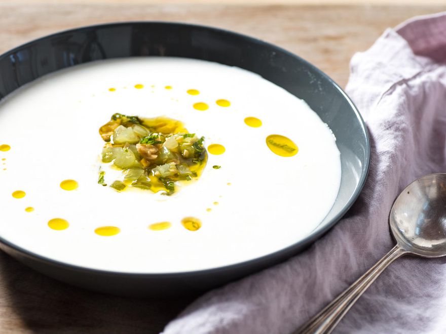 A bowl of ajo blanco garnished with green grapes, mint, and a drizzling of olive oil.