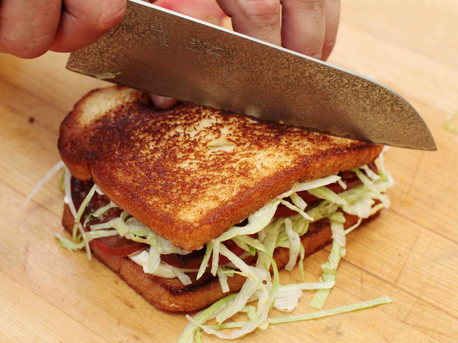 一把厨师用的刀把一个BLT三明治切成两半