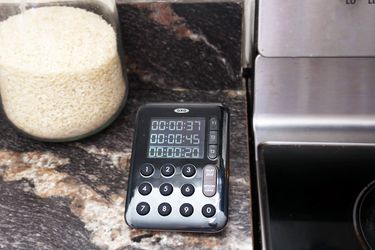 oxo triple stove timer with three times displayed on a countertop next to the stovetop
