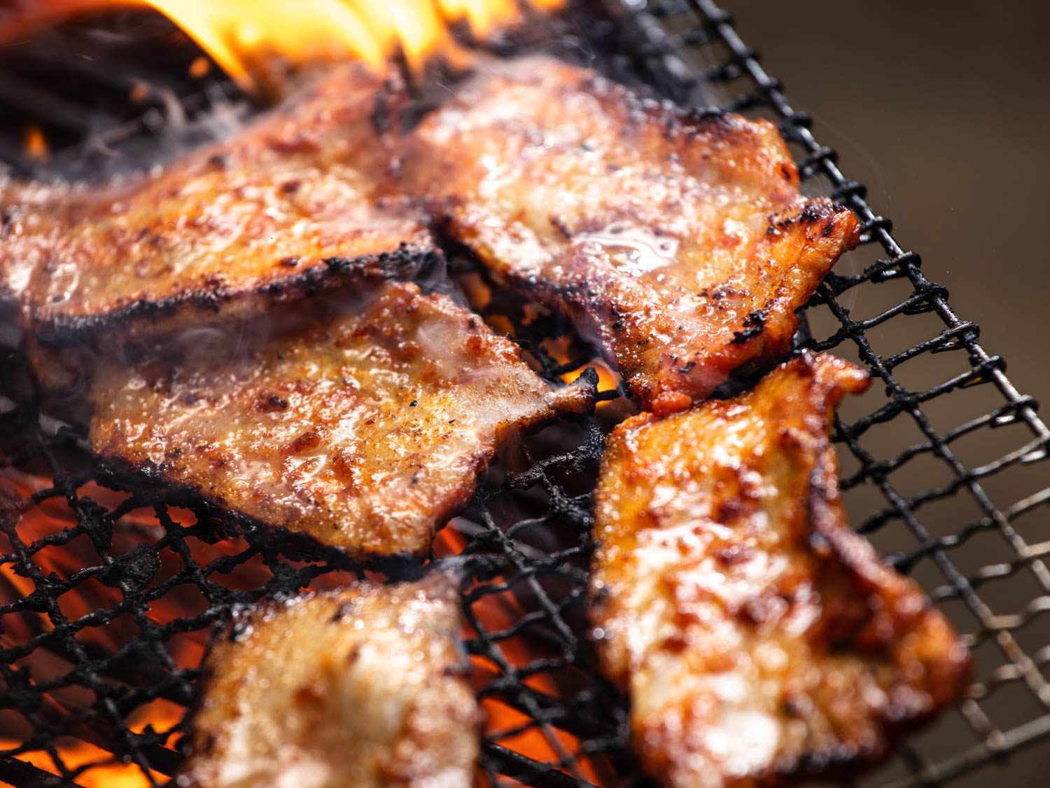 Pieces of pork belly sizzling on the grill.