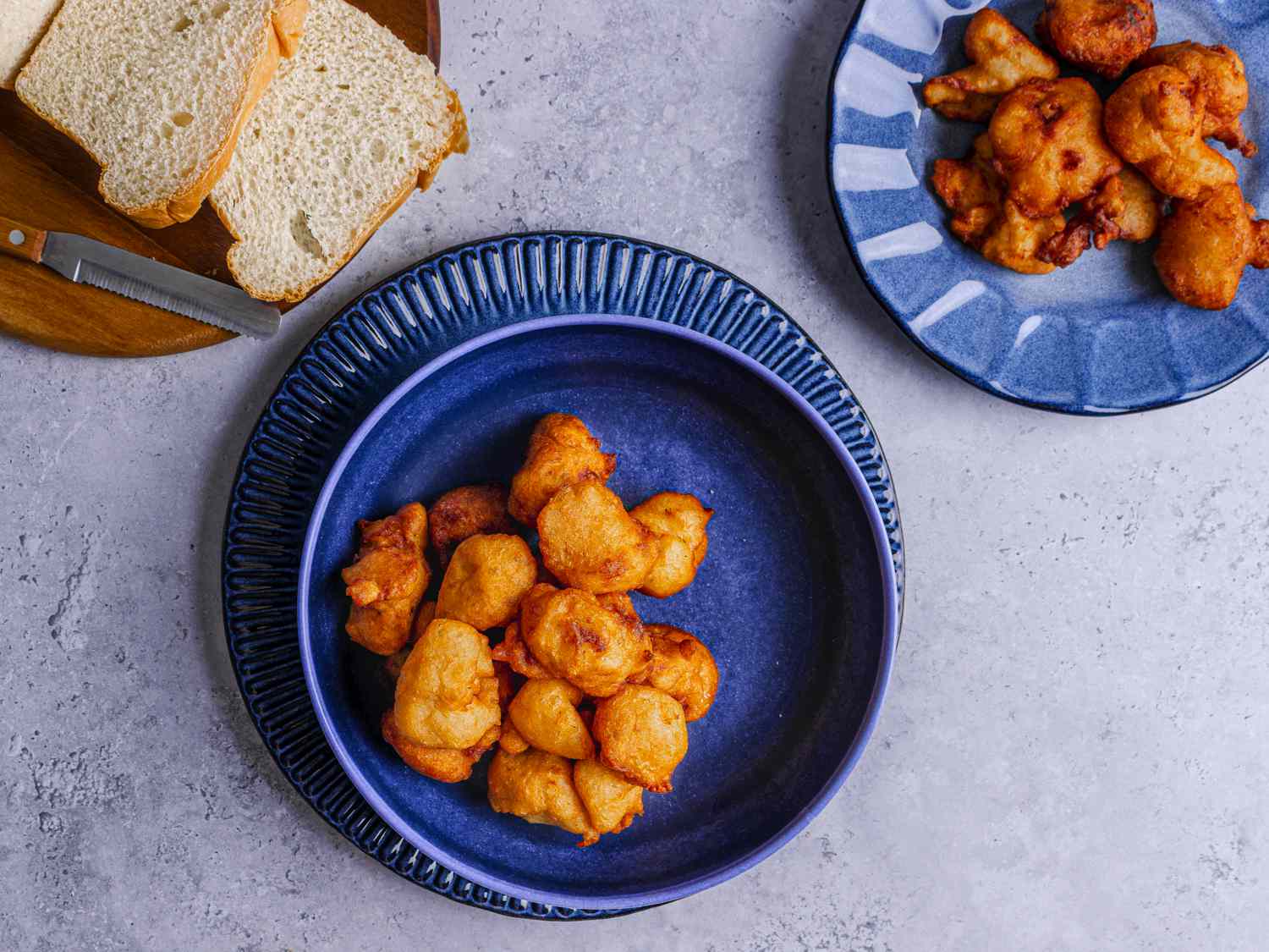 Akara on a deep blue bowl with a serving of white bread and a serving plate