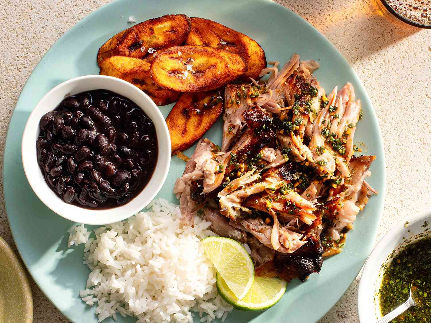 Shredded pork served with mojo sauce, rice, beans, and plantains