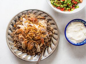 Hashweh with chicken served with a bowl of yogurt and farmers salad.