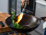 Blowtorching vegetables in a wok