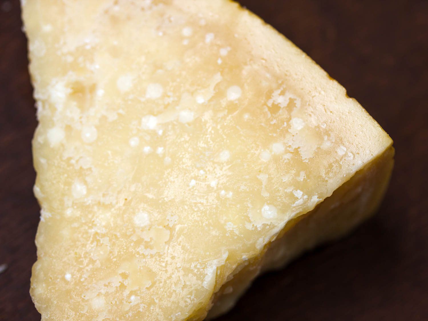 A piece of Parmesan cheese with crystals of protein visible.