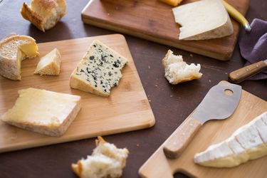 Wedges of different cheeses on cutting boards with cheese knives.