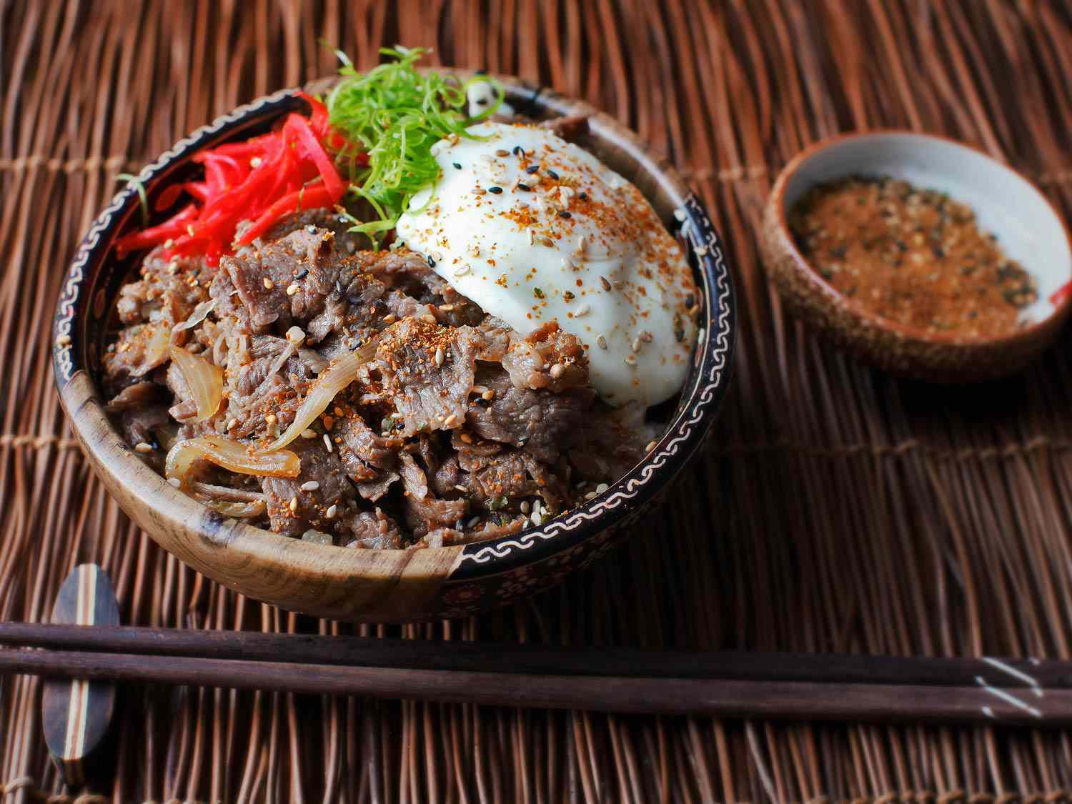 A Japanese simmered beef rice bowl with soft-cooked egg and pickled red ginger