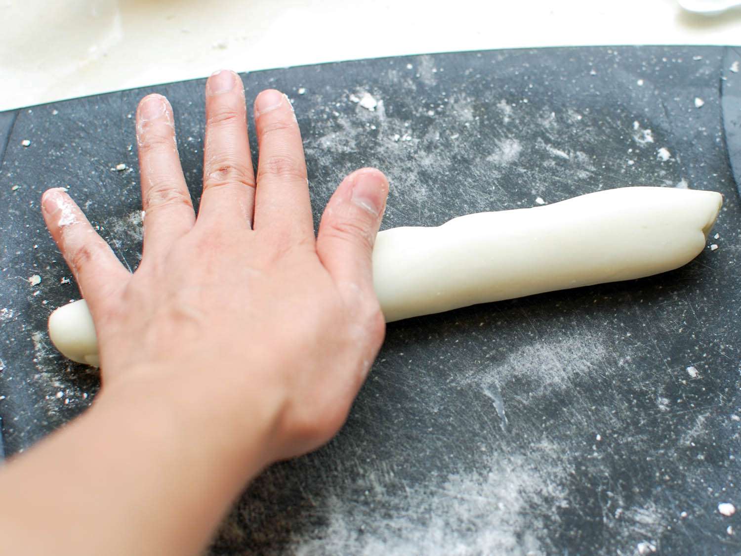 饺子皮在撒了面粉的切菜板上擀成长绳。