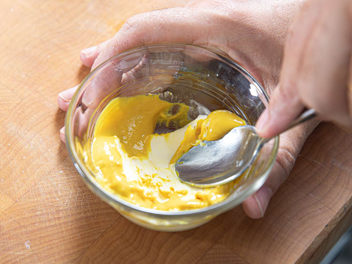 Overhead view of mixing butter and mustard in a small bowl