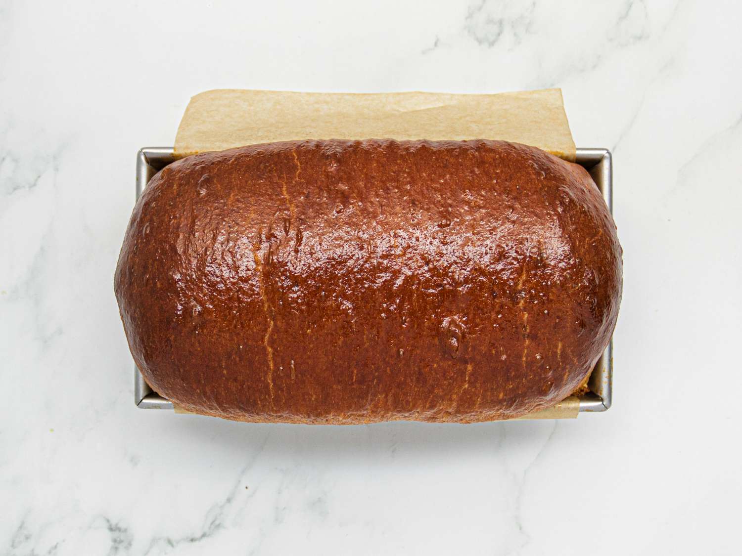 Overhead view of brioche loaf, golden brown, still in the pan, out of the oven